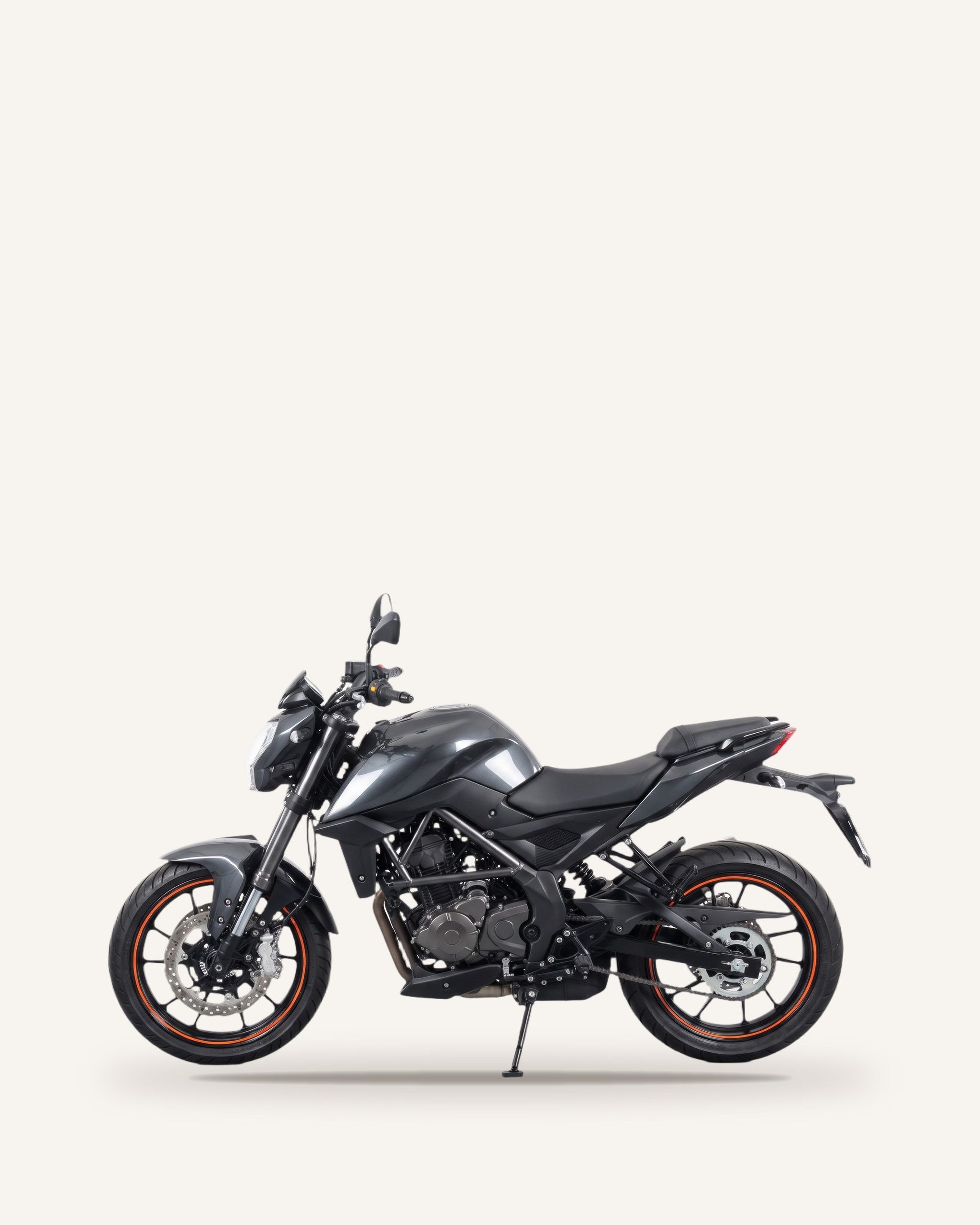 Siyah benzinli motosiklet, açıkta duran motor bloğu ve turuncu şeritli jantlar