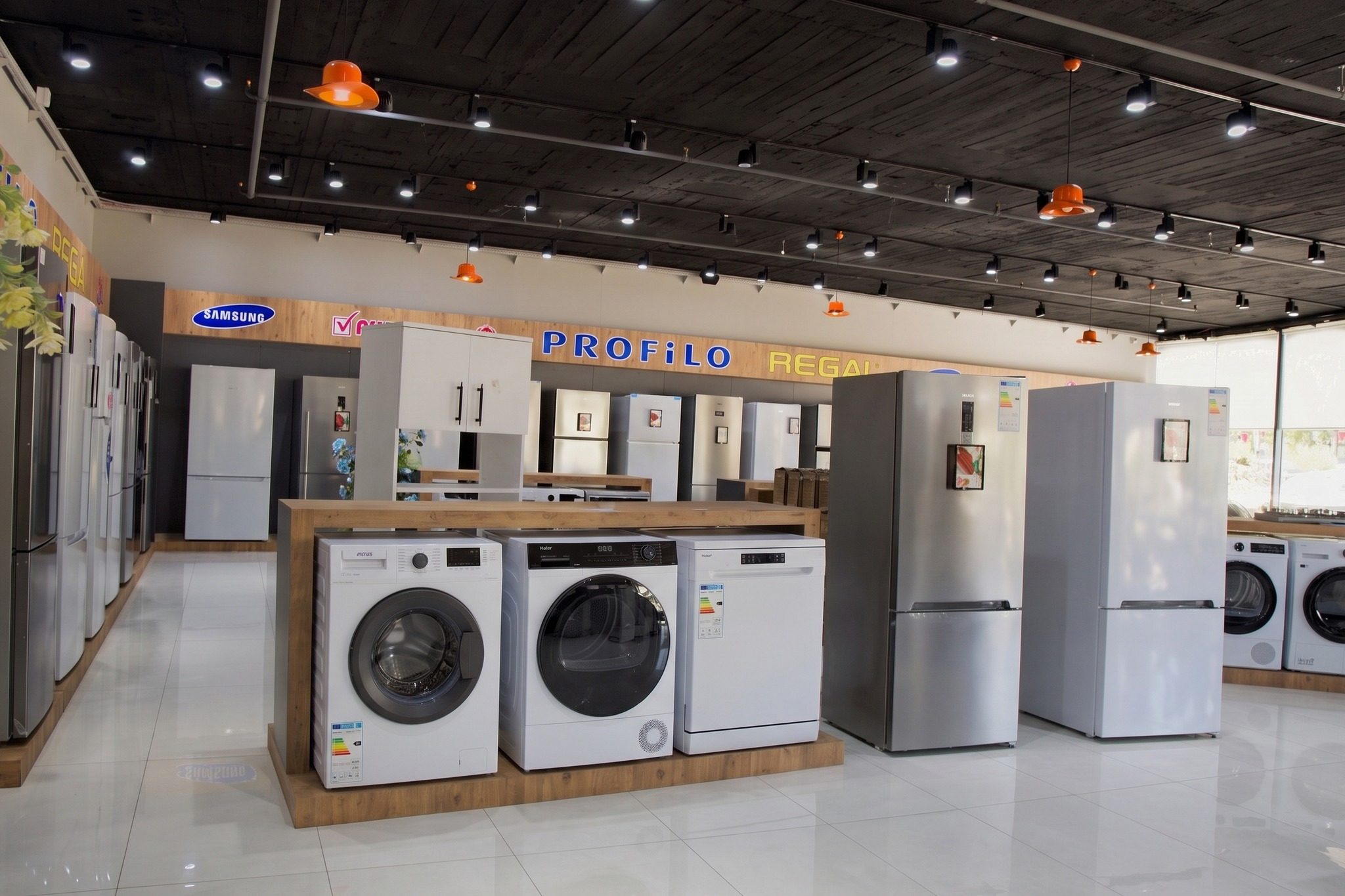 Mağaza içinde yan yana çamaşır makinesi, kurutma makinesi, bulaşık makinesi ve buzdolapları