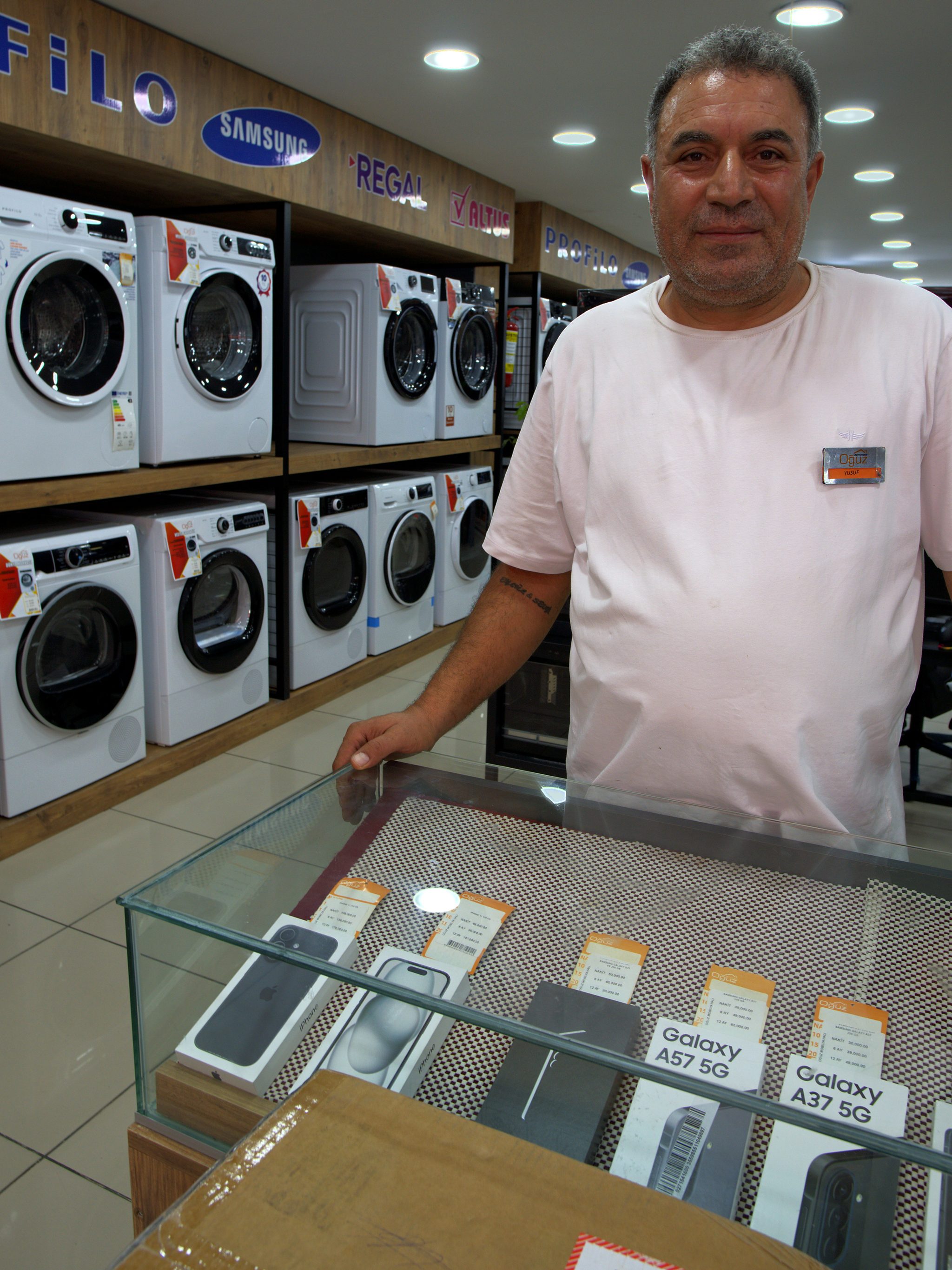 Telefon reyonunun bankosunda duran mağaza çalışanı