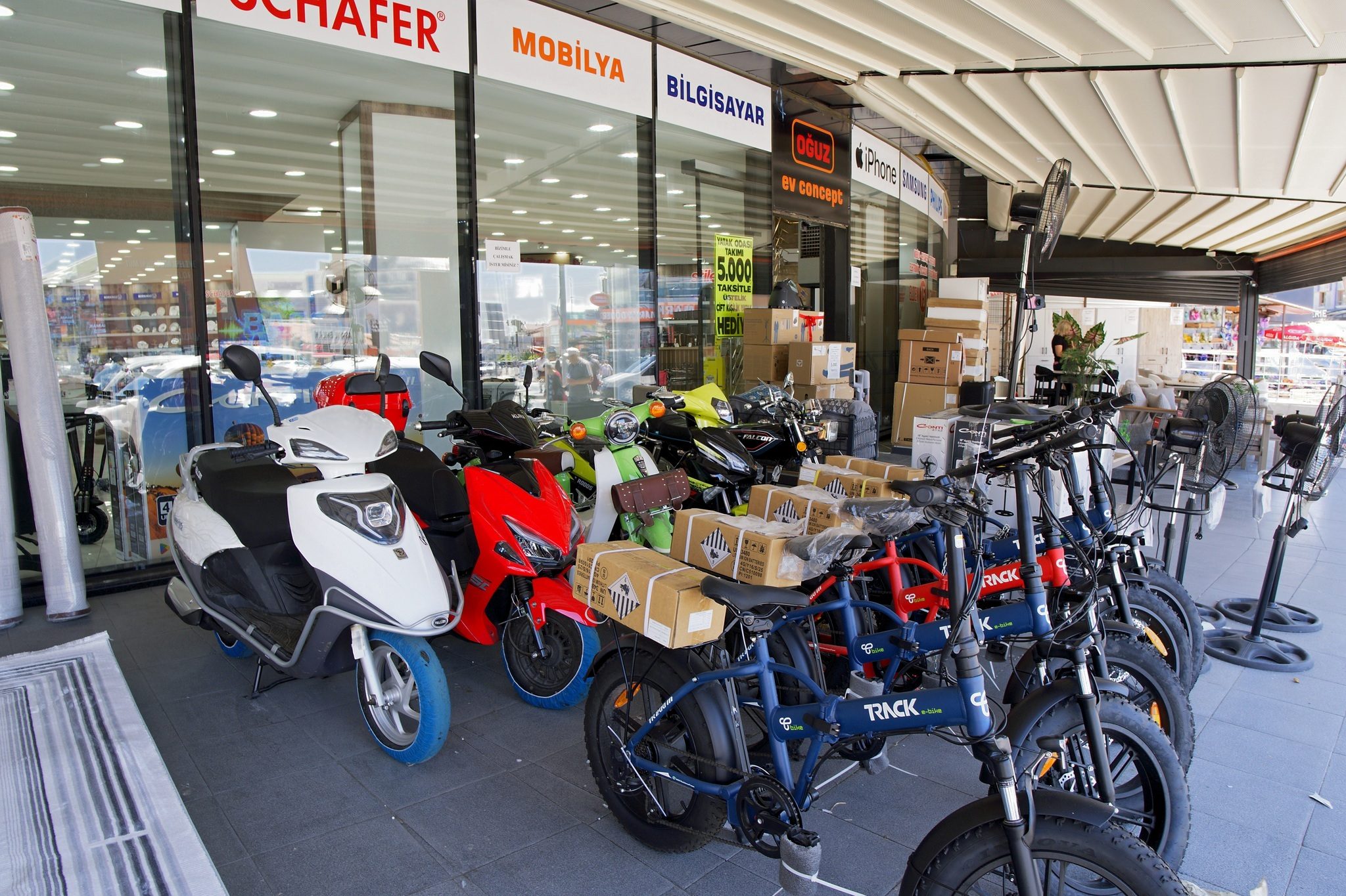 Hüseyingazi şubesinde sundurma altında sergilenen elektrikli bisiklet ve scooterlar, mağaza önü ve kaldırım teşhiri